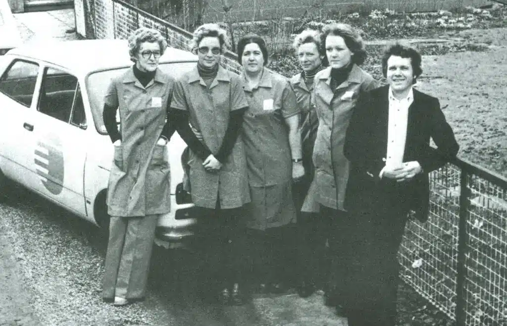 Historisk sort-hvidt foto af Peer og fem rengøringsmedarbejdere ved en bil